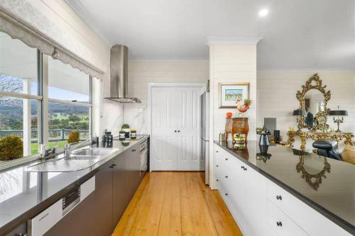 cocina grande con encimeras blancas y ventana grande en IRONBARK FARM Farmhouse on 52 acres in the scenic Yarra Valley, en Glenburn