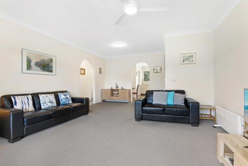 a living room with two black couches and a table at Hawaiian Gardens 22 in Coffs Harbour