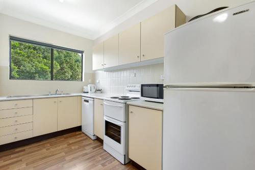 a kitchen with white appliances and a large window at Hawaiian Gardens 22 in Coffs Harbour