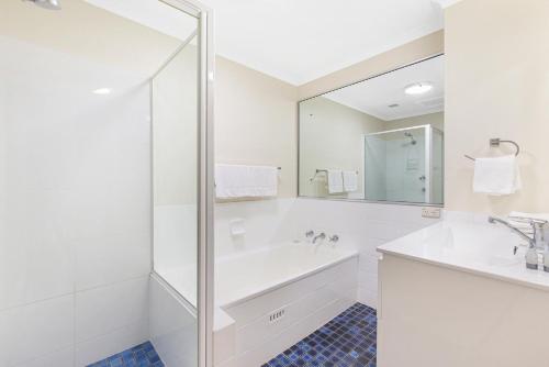 a white bathroom with a tub and a sink at Hawaiian Gardens 22 in Coffs Harbour