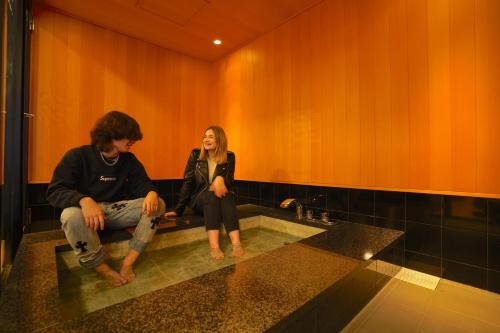 a man and a woman sitting on a sink in a bathroom at COGO Ryogoku in Tokyo