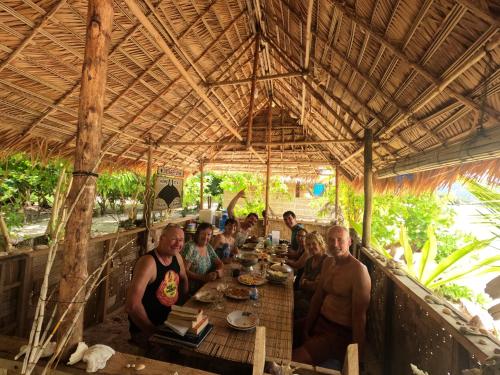 a group of people sitting at a table in a restaurant at Snonbepur homestay Raja Ampat in Sageurin