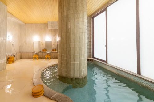 a swimming pool with a large column in a building at Yumotoya in Matsumoto