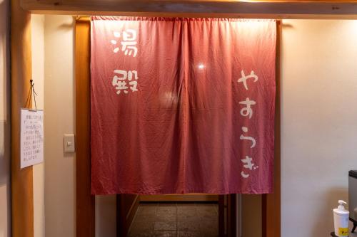 a red curtain with asian writing on a door at Yumotoya in Matsumoto