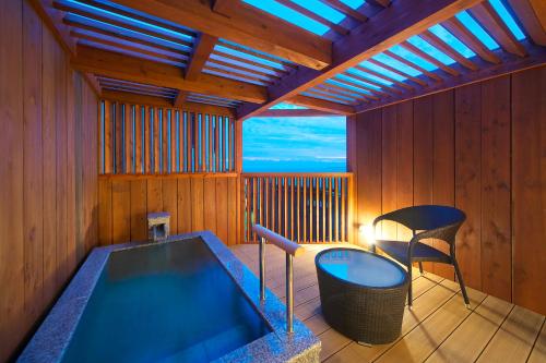 a bathroom with a tub and a chair in it at Umiusagi in Higashiizu