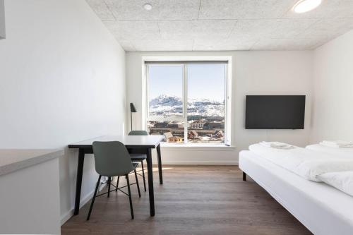 um quarto com uma secretária, uma cama e uma televisão em Hotel Aurora Apartments em Nuuk