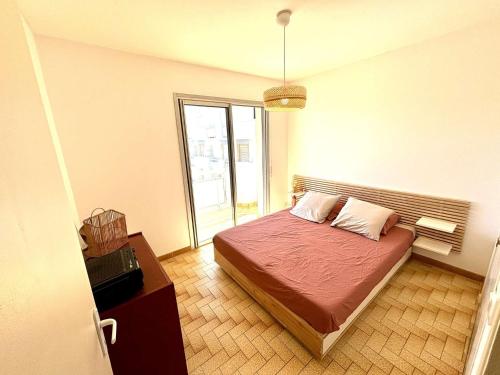 une chambre avec un lit et une grande fenêtre dans l'établissement Appartement traversant, proche plage, 2 balcons, pets ok, ménage inclus, jusqu’à 8 pers, Port-la-Nouvelle - FR-1-229C-94, à Port-la-Nouvelle