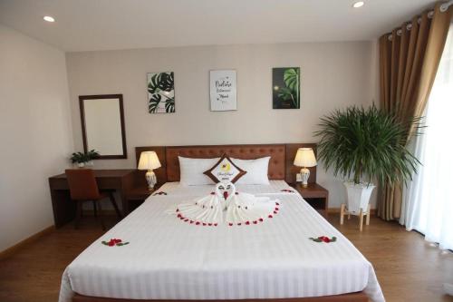 a bedroom with a large white bed with flowers on it at Sea Angel HOTEL Tuần Châu Hạ Long in Ha Long