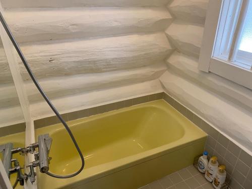 baño con bañera amarilla y ventana en Cottage Jokigen, en Yamanakako
