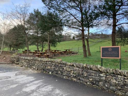 a stone wall with a sign in front of a park at The Sun Inn in Windermere