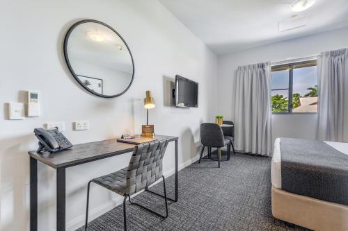 a hotel room with a desk and a bed and a mirror at Hudson Parap in Darwin