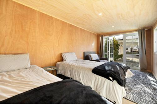 two beds in a small room with a window at Fletcher Cottage in Arrowtown