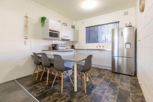 a kitchen with a table and a stainless steel refrigerator at Forster Holiday Lodge 4 in Forster