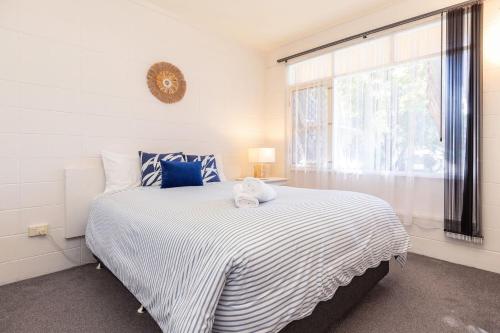 a white bedroom with a large bed with a window at Forster Holiday Lodge 4 in Forster