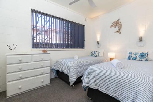a bedroom with two beds and a dresser and a window at Forster Holiday Lodge 4 in Forster