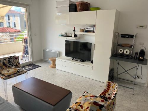 a living room with a tv and a table at Modern Condo w Terrace 250m from Beach & Pool in Antibes