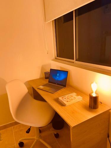 a laptop computer sitting on a wooden desk with a chair at Apartamento Exclusivo - Caribe Campestre Coveñas in Coveñas