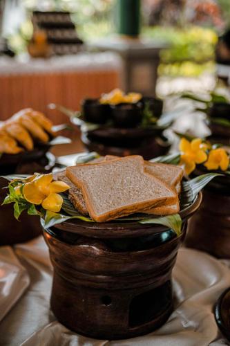 une table avec des sandwichs et des fleurs sur une table dans l'établissement Margo Utomo Hill View Resort, à Banyuwangi