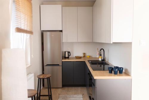 a kitchen with white cabinets and a stainless steel refrigerator at Apartament Kościuszki Chorzów in Chorzów