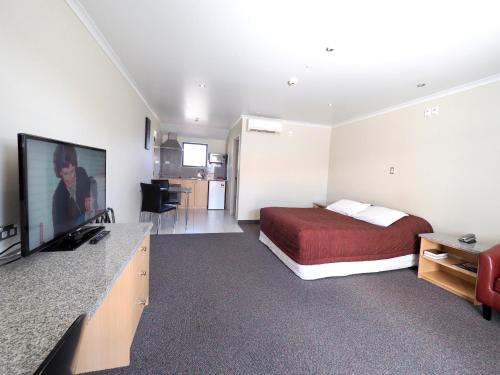 a hotel room with a bed and a flat screen tv at Ulster Lodge Motel in Hamilton