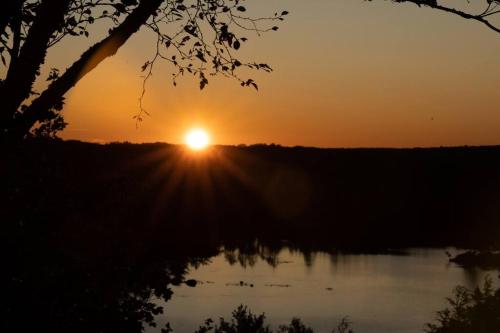 a sunset over a lake with the sun setting at The Eagle's Landing on Minamkeak Lake - A Serene Escape in Italy Cross