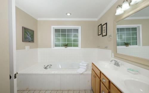 a white bathroom with two sinks and a large tub at Hen Wallow Creek Cottage in Cosby