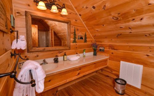 uma casa de banho com um lavatório e um espelho num chalé de madeira em Like a Comet em Sevierville