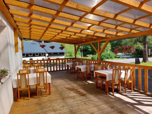 ein Restaurant mit Tischen und Stühlen auf einer Holzterrasse in der Unterkunft Hotel Bartošovice in Bartošovice v Orlických Horách