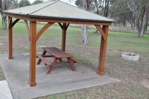 a wooden picnic table and bench in a park at Pokolbin Village Estate in Pokolbin