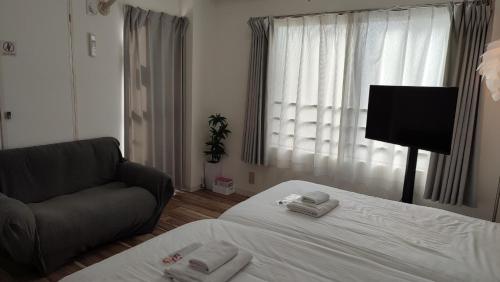 a bedroom with a bed and a couch and a window at Sun Park Heights in Kobe