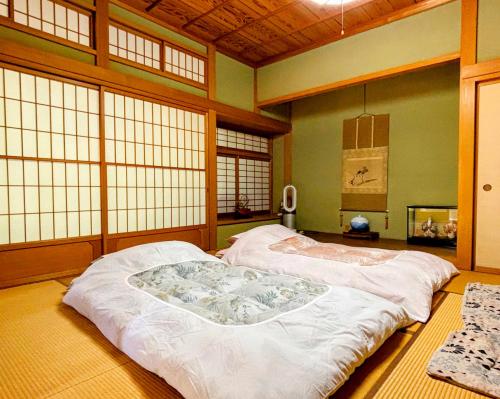 um quarto com uma cama grande num quarto com janelas em 富士吉田かつまたや em Fujiyoshida