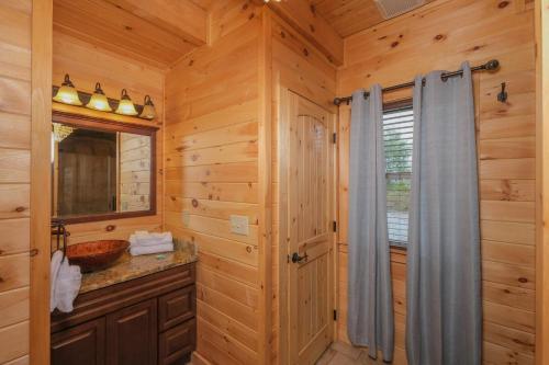a log cabin bathroom with a sink and a mirror at Swept Away in Gatlinburg