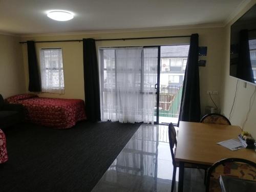 a living room with a couch and a table and a window at Ulster Lodge Motel in Hamilton