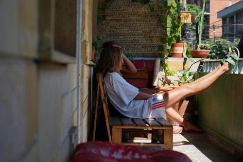 a woman sitting on a balcony with her legs up at Casa Almarita - Hostal, Bar y Restaurante in Medellín