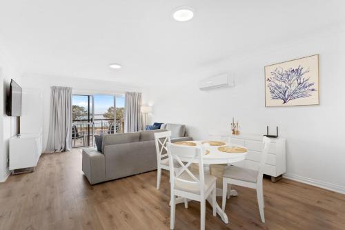sala de estar blanca con mesa y sofá en Nautica Residences Hillarys en Perth