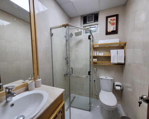 a bathroom with a shower and a toilet and a sink at Camphor Hotel in Ras al Khaimah