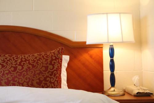 um candeeiro numa mesa de cabeceira ao lado de uma cama em Arcadia Hotel em Gering
