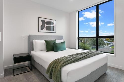 una camera bianca con un grande letto e una finestra di Urban Rest Sylvia Park Apartments ad Auckland