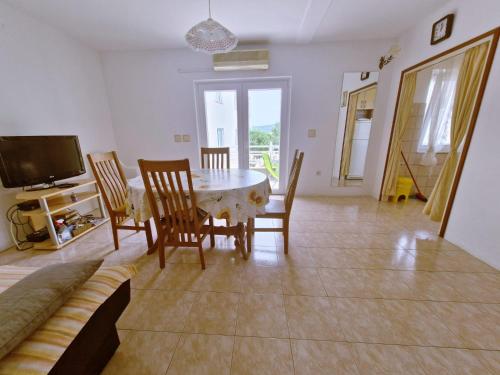 uma sala de jantar com mesa e cadeiras e uma televisão em Apartments Mira - 20 m from pebble beach em Zaboric