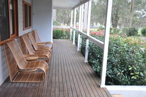 three benches sitting on the porch of a house at Pokolbin Village Estate in Pokolbin