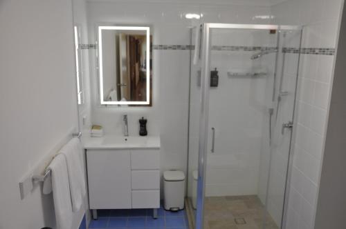 a white bathroom with a shower and a sink at Pokolbin Village Estate in Pokolbin
