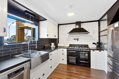 uma cozinha com armários brancos e electrodomésticos pretos em Nautica Residences Hillarys em Perth