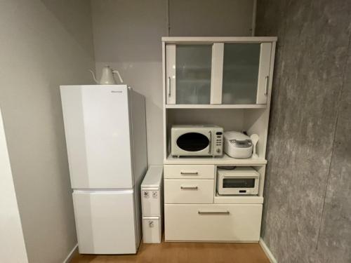 a small kitchen with a refrigerator and a microwave at Mt Fuji view! Cottage JOKIGEN House F in Yamanakako