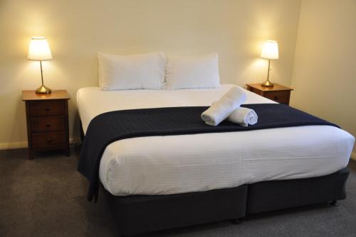 a bedroom with a large bed with two lamps at Pokolbin Village Estate in Pokolbin