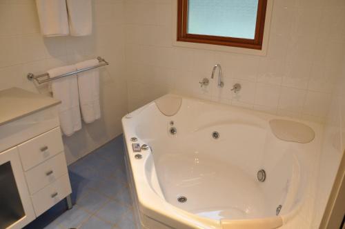 a white bath tub in a bathroom with a sink at Pokolbin Village Estate in Pokolbin