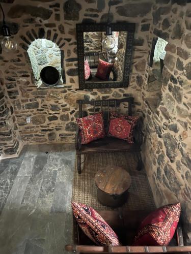 a room with a stone wall with a table and pillows at Byzantine Home in the Castle in Mesta