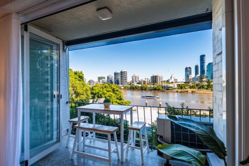 a balcony with a table and chairs and a view of a river at Skyline and Riverview 2 bedrooms apartment in Brisbane