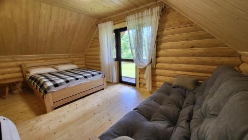 a room with a bed and a couch in a log cabin at Котеджі Карпати Fest in Mizhhirʼʼya