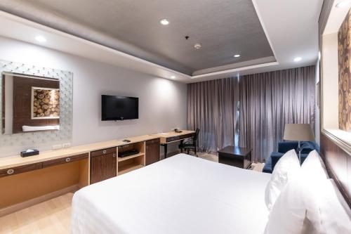 a hotel room with a bed and a desk and a tv at Admiral Premier Bangkok in Bangkok