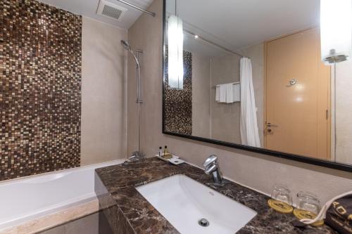 a bathroom with a sink and a large mirror at Admiral Premier Bangkok in Bangkok